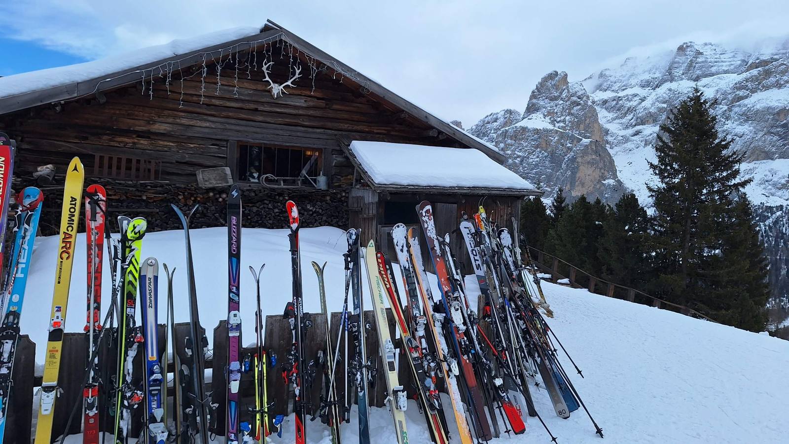 Skis leaning against a snow-covered log hut in the Dolomites