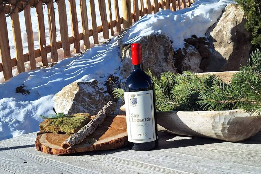A bottle of red wine on a wooden barrel table in the snow