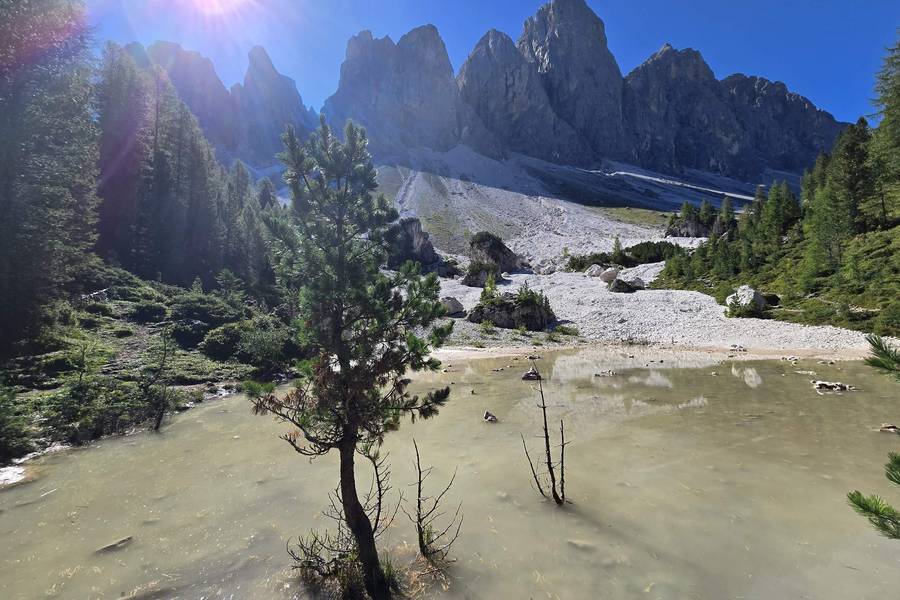 Odle peaks above a mountain pond in sunlight