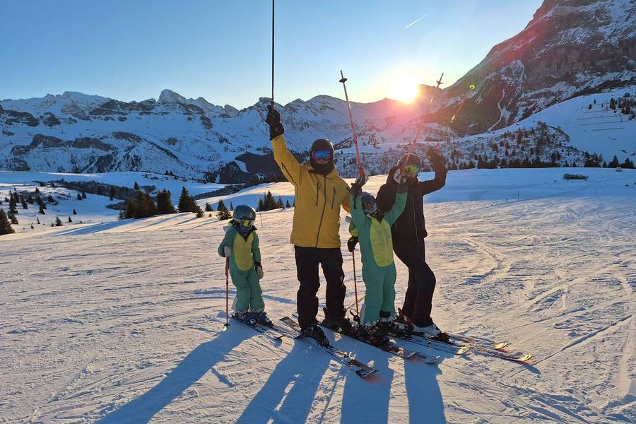 Skiers raising their poles at sunset on a Dolomites slope