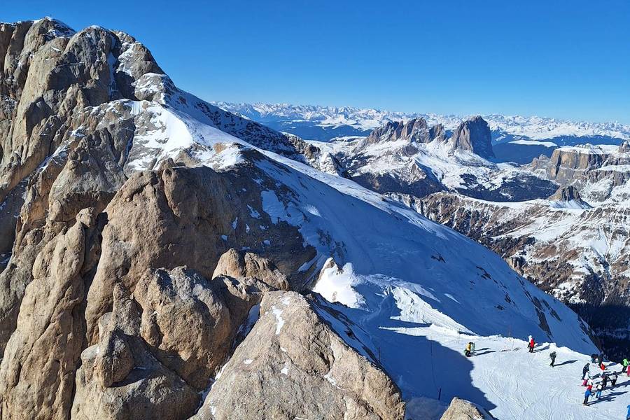 Rocky summit with a wide view over the snow-covered Dolomites