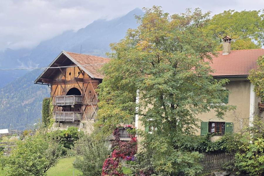 Traditional South Tyrolean farmhouse with a wooden barn in autumn, with misty mountains behind