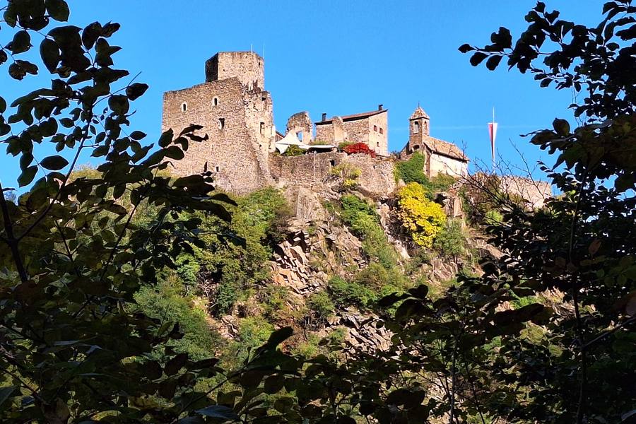 Medieval castle on a rocky hill above South Tyrol, seen through autumn leaves